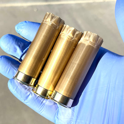 Three gold spent Remington cartridges held in a blue gloved hand.