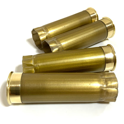 Four gold 12 gauge shotgun hulls stacked horizontally on a plain white background showing open crimped ends.