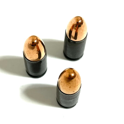 Three gray steel 9mm dummy cartridges standing upright, viewed from above showing rounded bullet tips