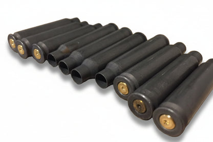Ten dark gray steel .223/5.56 empty cases in a row showing brass-colored spent primers and open case mouths