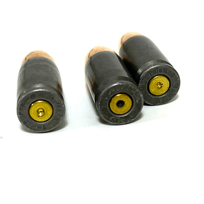 Three gray steel 9mm dummy cartridges shown base-first with gold-colored spent primers visible