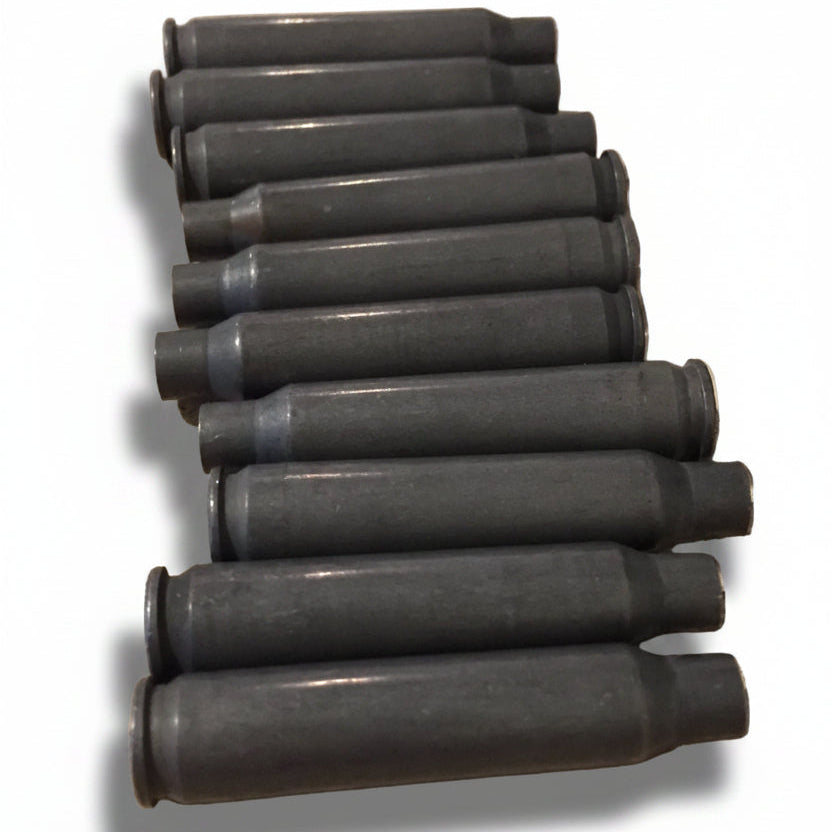 Ten dark gray steel spent .223/5.56 empty shells lying in a stacked diagonal row on a stone counter