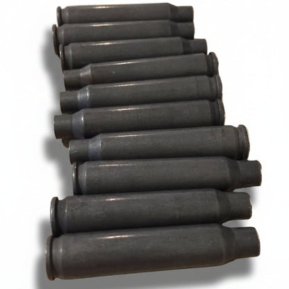 Ten dark gray steel spent .223/5.56 empty shells lying in a stacked diagonal row on a stone counter