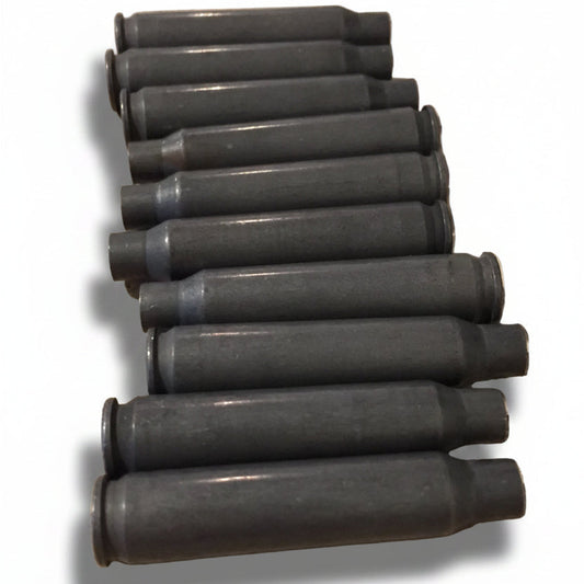 Ten dark gray steel spent .223/5.56 empty shells lying in a stacked diagonal row on a stone counter