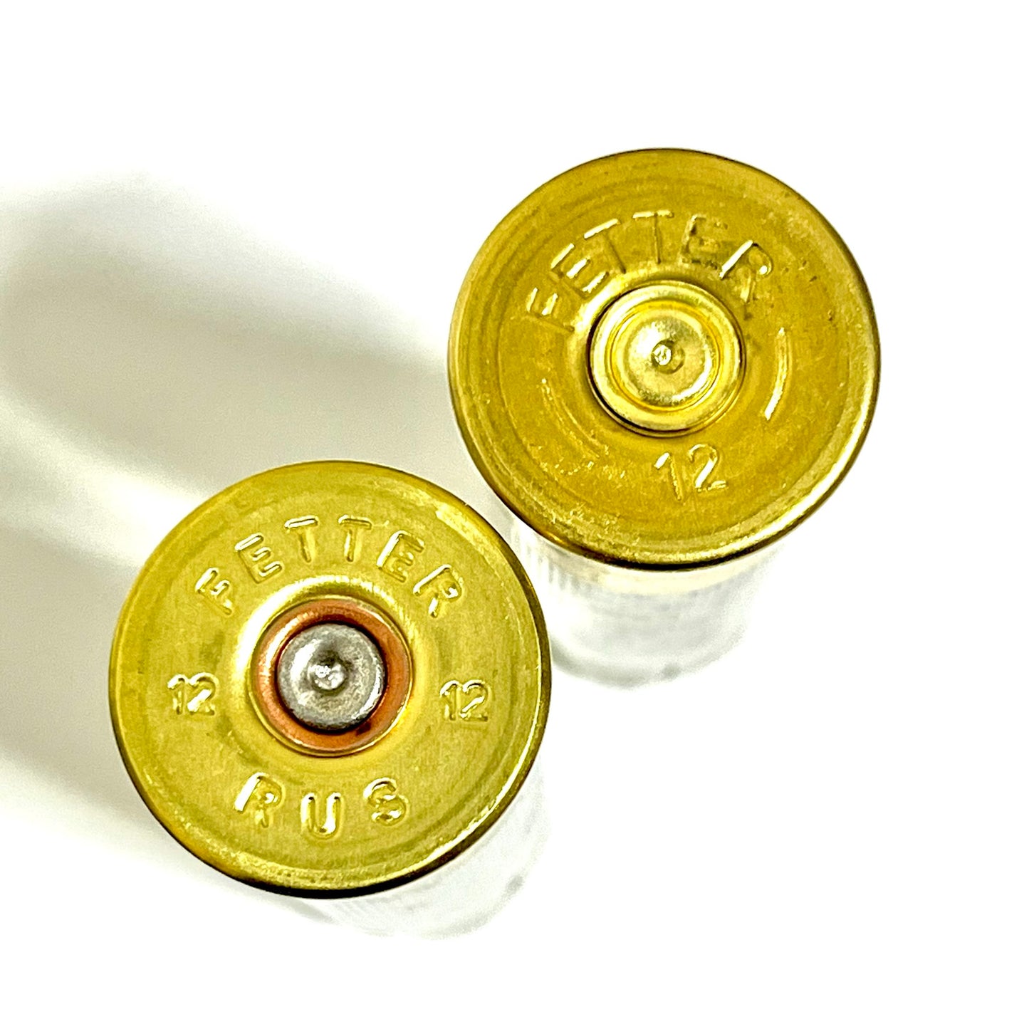 Close-up of two semi-translucent 12 gauge Fetter Russian shotgun shells showing gold headstamps