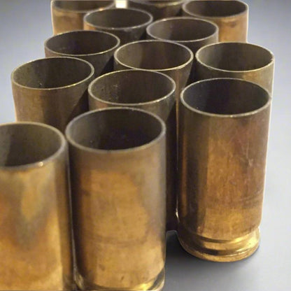 Close-up low angle view of uncleaned 9mm brass cases standing upright showing open top rims and hollow mouths.
