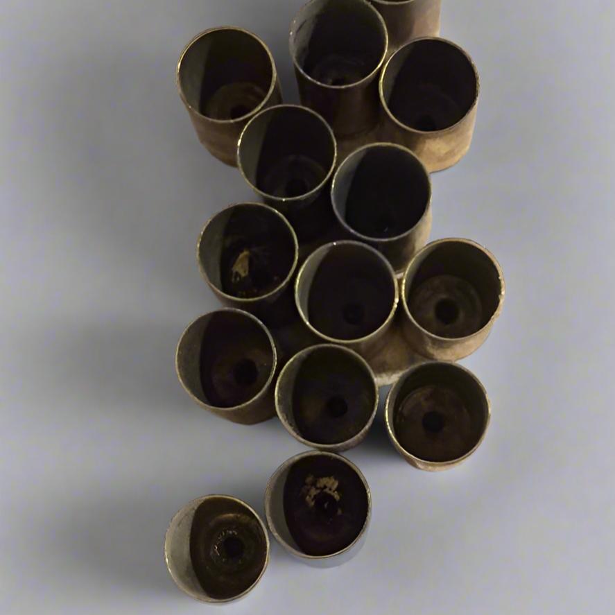 Top-down view looking into the hollow interior cavities of thirteen uncleaned 9mm brass casings.