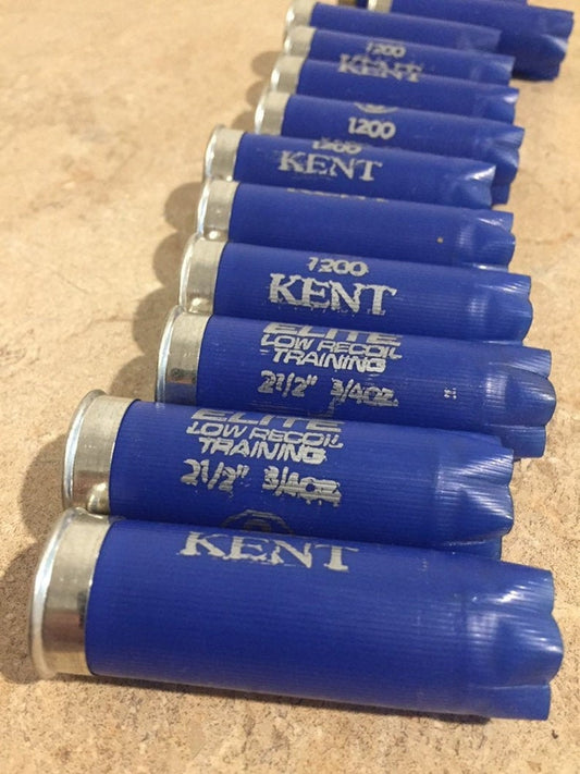Vertical row of navy blue Kent 12-gauge empty shotgun shells arranged on a textured surface showing silver metal bases and open star crimps.
