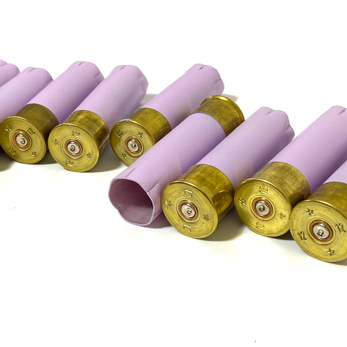 Row of lavender purple 12 gauge shotgun shells with gold bases lying at an angle showing headstamps