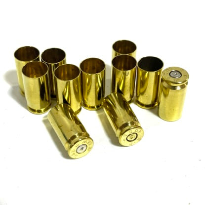 11 polished 40 S&W brass casings arranged on a white background, with five standing upright to show the primer pockets and four lying flat to display the smooth tumbled sides.