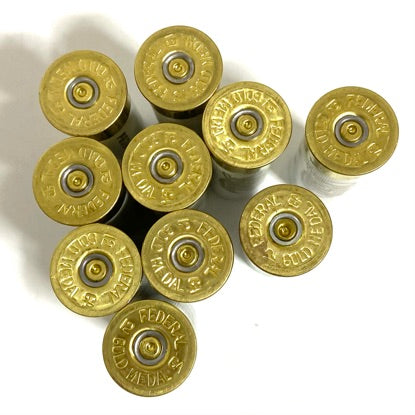 Ten white empty shotgun shell bases stamped Federal Gold Medal, arranged in a cluster and viewed from below.