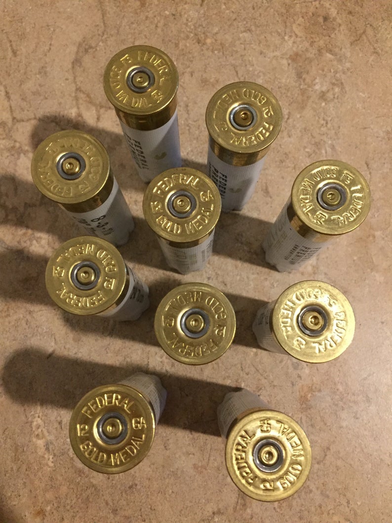 10 white Federal Gold Medal 12 gauge shotgun shells arranged in a circle showing brass headstamps