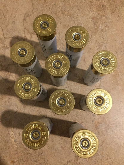 10 white Federal Gold Medal 12 gauge shotgun shells arranged in a circle showing brass headstamps