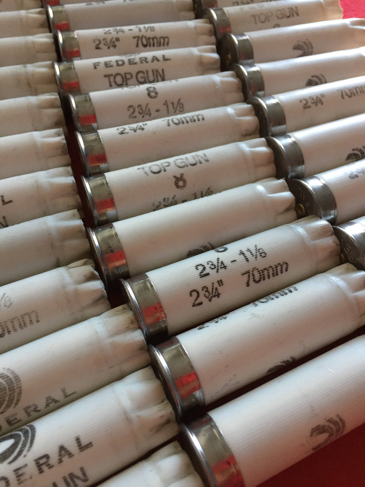 Rows of white Federal Top Gun shotgun shells lying diagonally, showing printed “2 3/4-1 1/8, 70mm” load markings
