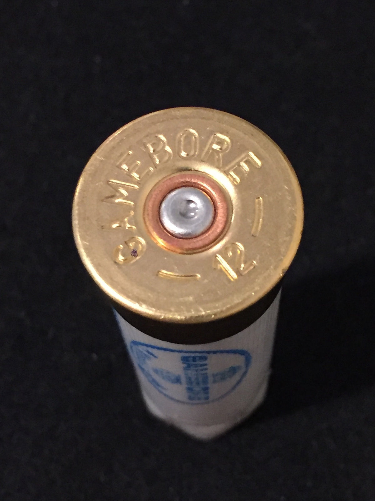 Close-up of a gold brass shell head embossed "Gamebore 12" with a white shell body below