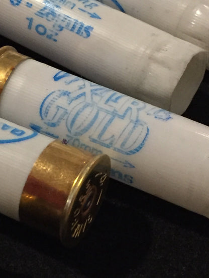 Close-up of white shotgun shells with brass bases showing "White Gold" printed text