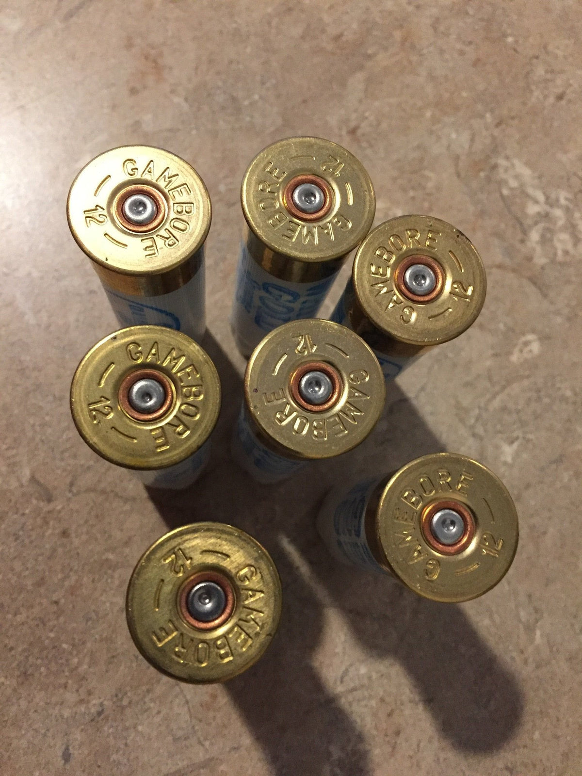 7 gold brass shell heads viewed from above embossed "Gamebore 12"