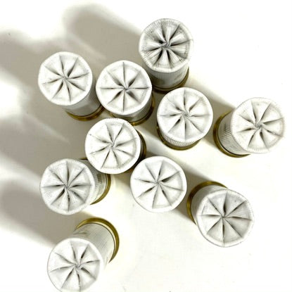 Ten white once-fired hulls with star-crimped tops arranged in a cluster, viewed from directly above on a white background.