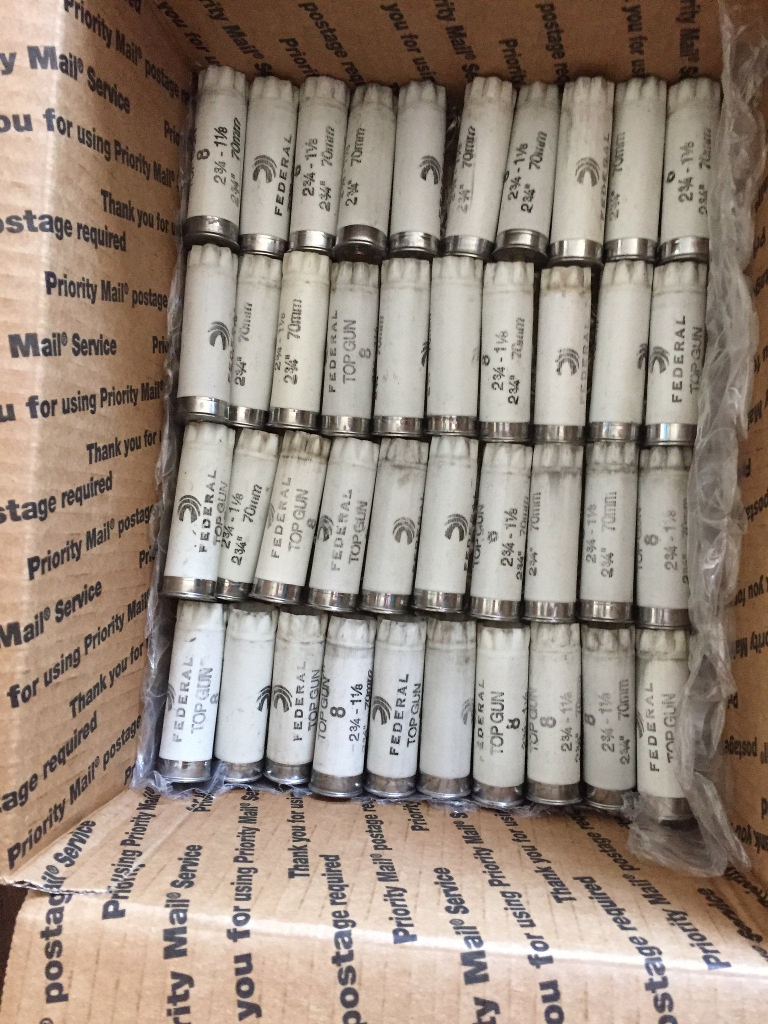 Rows of white Federal Top Gun shotgun shells packed inside a Priority Mail shipping box