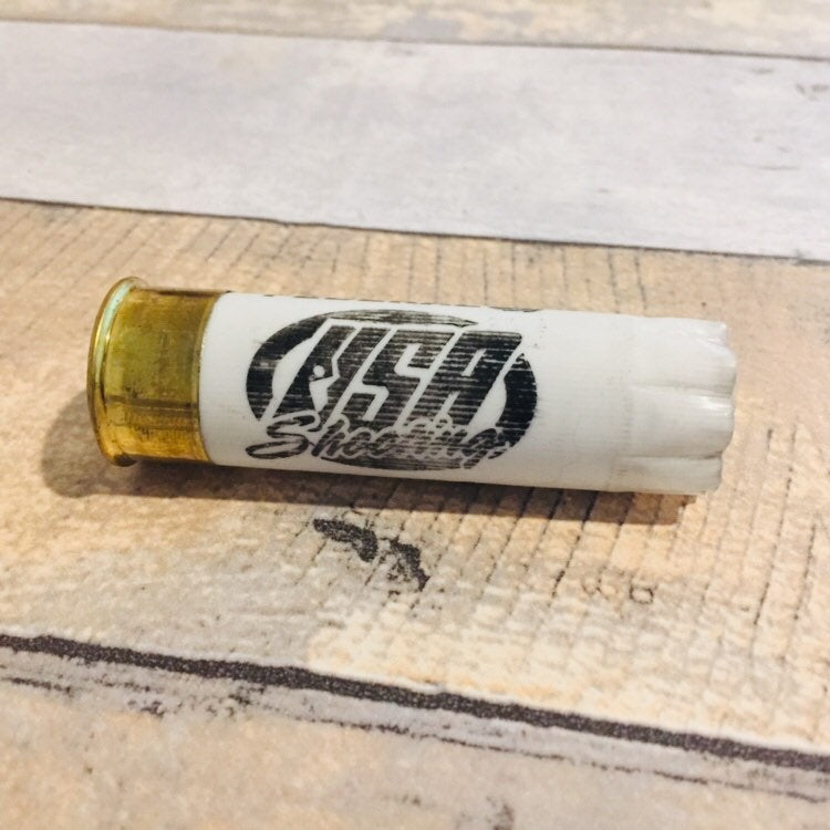 Single empty white 12 gauge USA Shooting shotgun shell with brass base on a wood deck