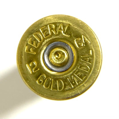 Close-up of a once-fired white headstamp stamped Federal 12 GA Gold Medal, showing a spent primer in the center.