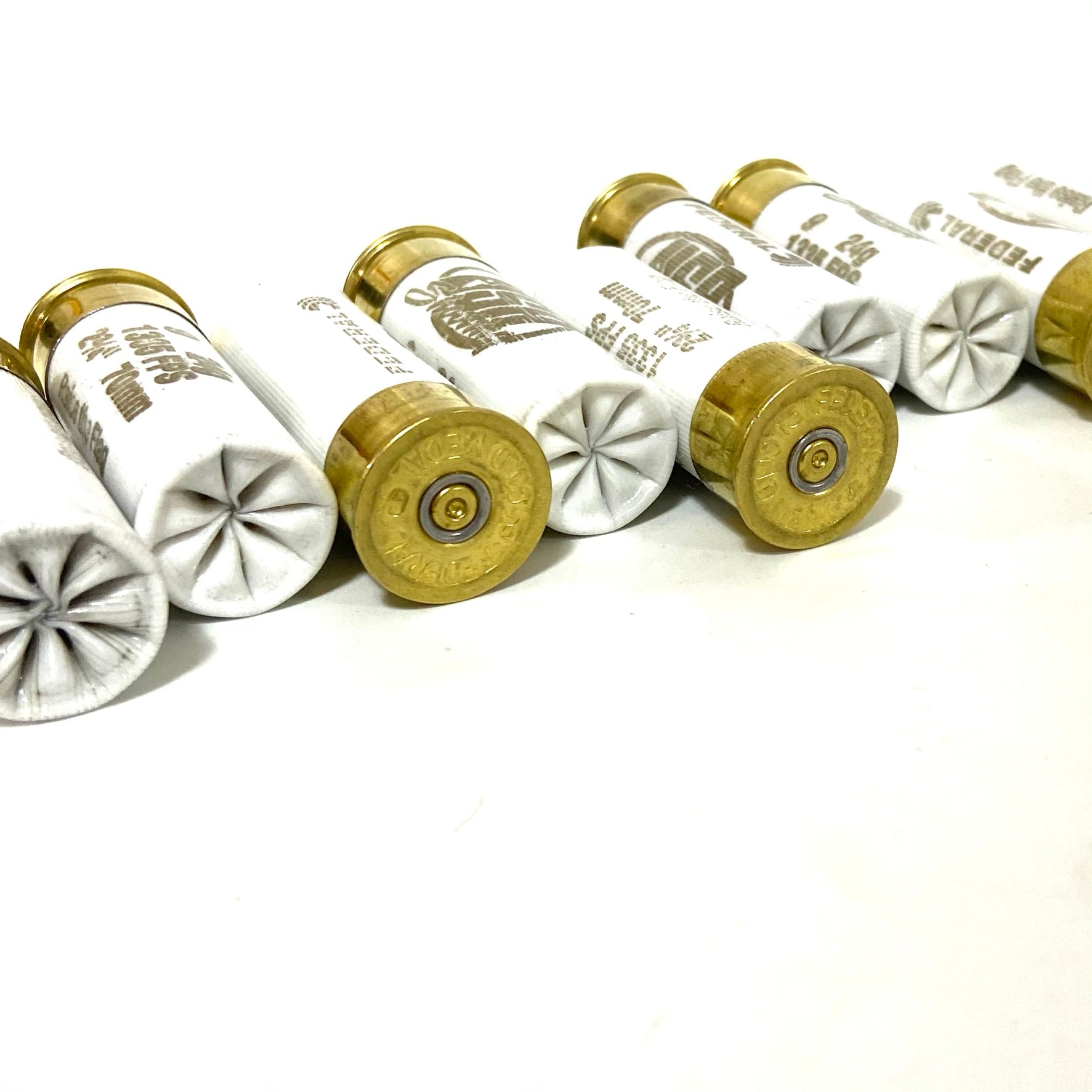 White used hulls alternating star-crimped tops and brass bases in a staggered row on a white surface.