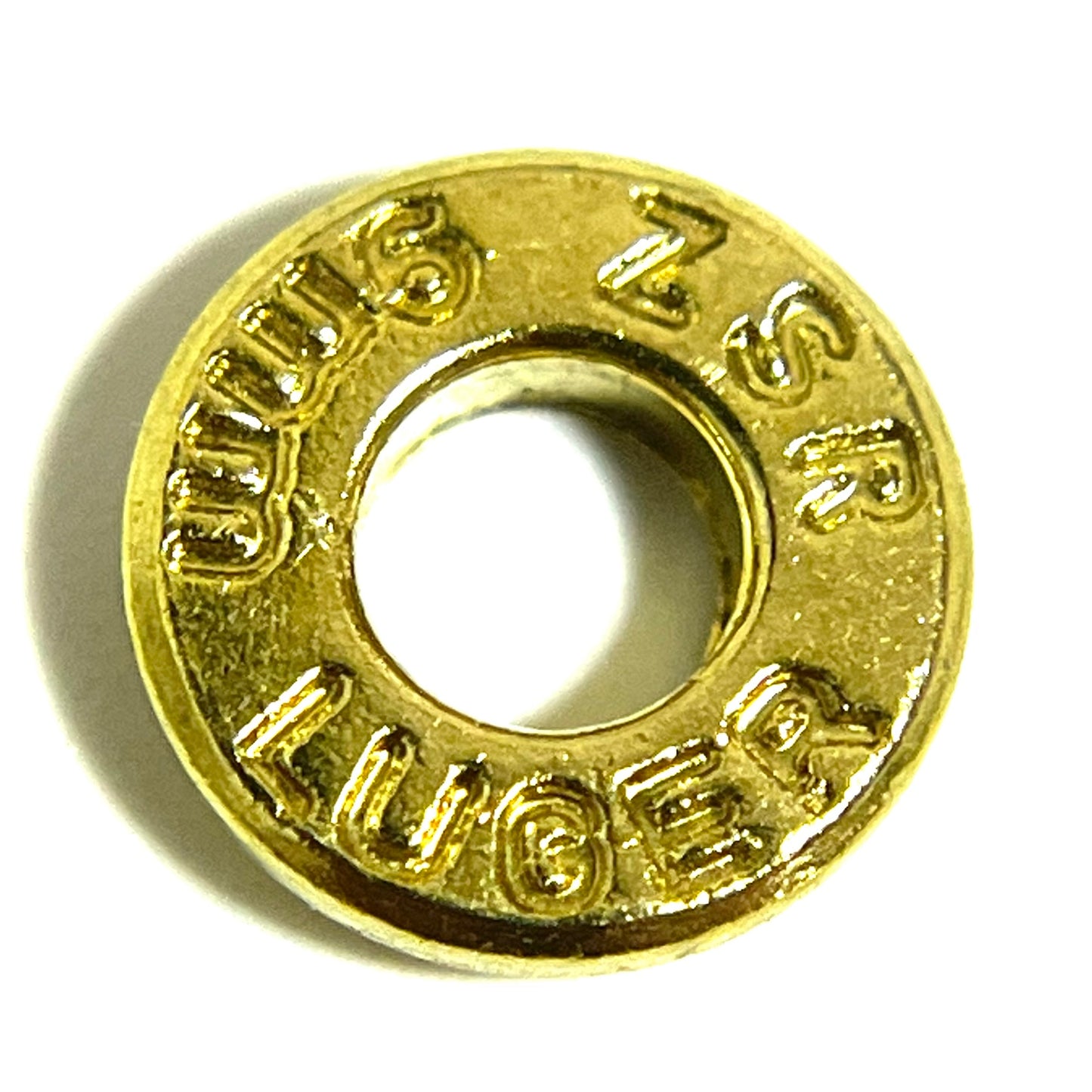 A single brass deprimed slice stamped 9mm Luger, viewed in a close-up shot with a hollow center.