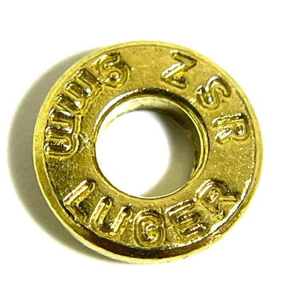 A single brass deprimed slice stamped 9mm Luger, viewed in a close-up shot with a hollow center.