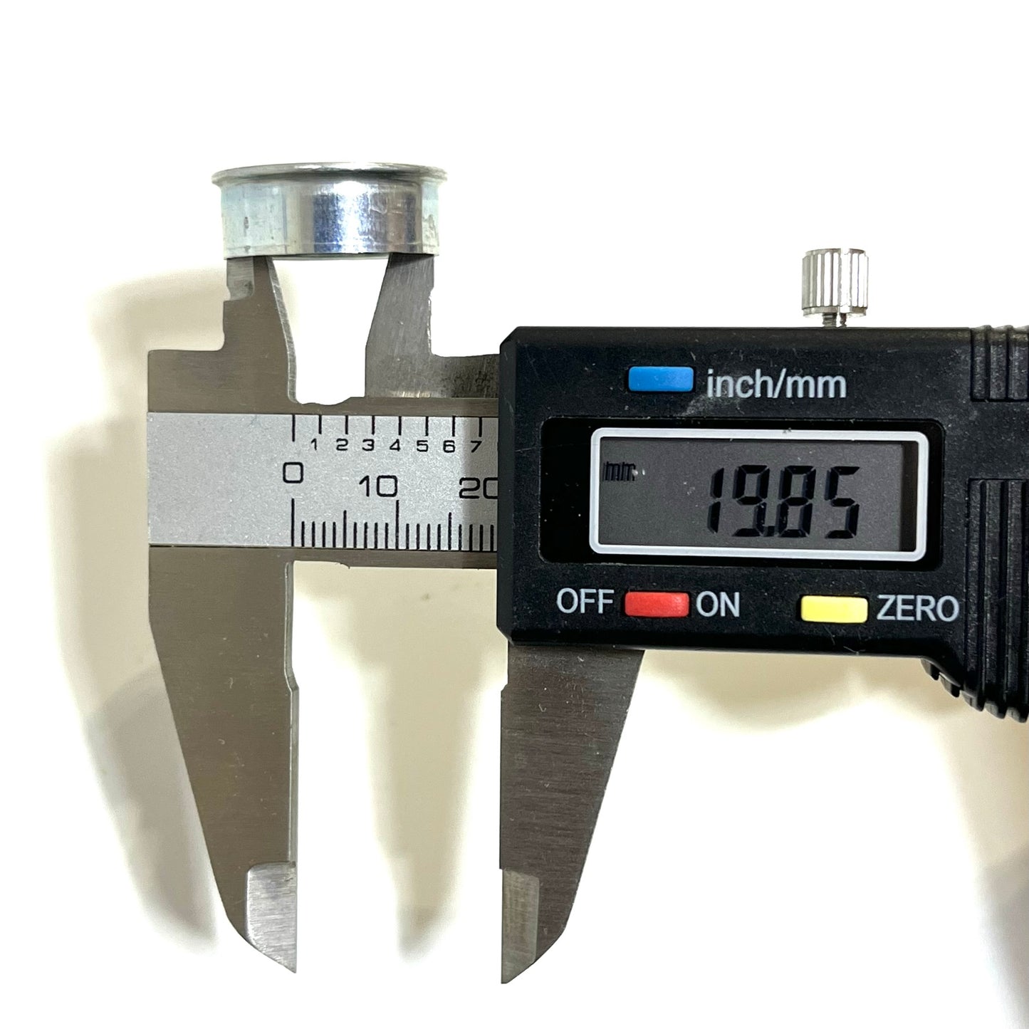 Digital caliper measuring the diameter of a silver Winchester 12 gauge deprimed steel bottom, reading 19.85mm
