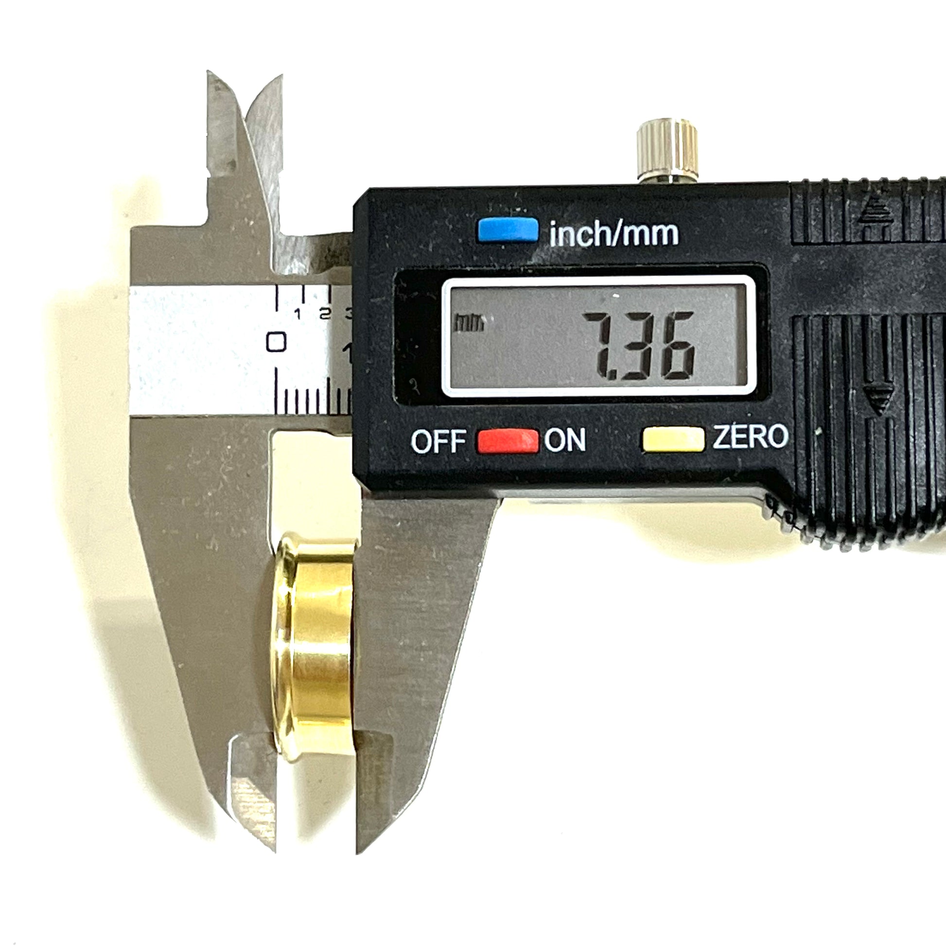 Digital caliper measuring a gold brass shell head, display reading 7.36mm
