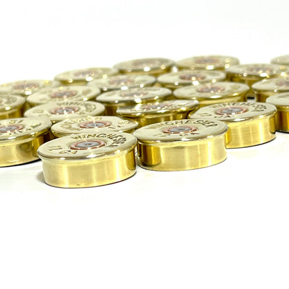 Cluster of gold brass shell heads with "Winchester 12 GA" headstamp text on a white background, angled view