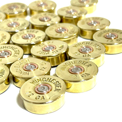 Cluster of gold brass shell heads with "Winchester 12 GA" headstamp text on a white background