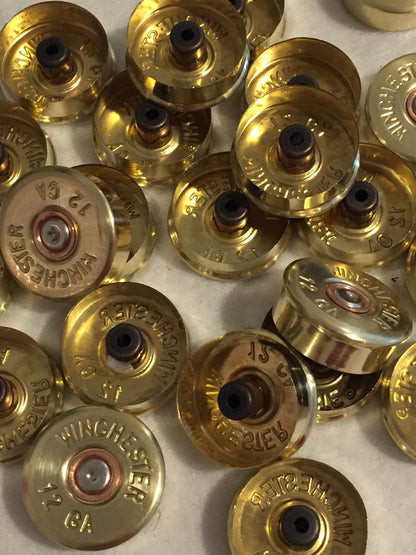 Gold brass shell heads showing hollow primer pockets and "Winchester 12 GA" headstamps, upside-down view