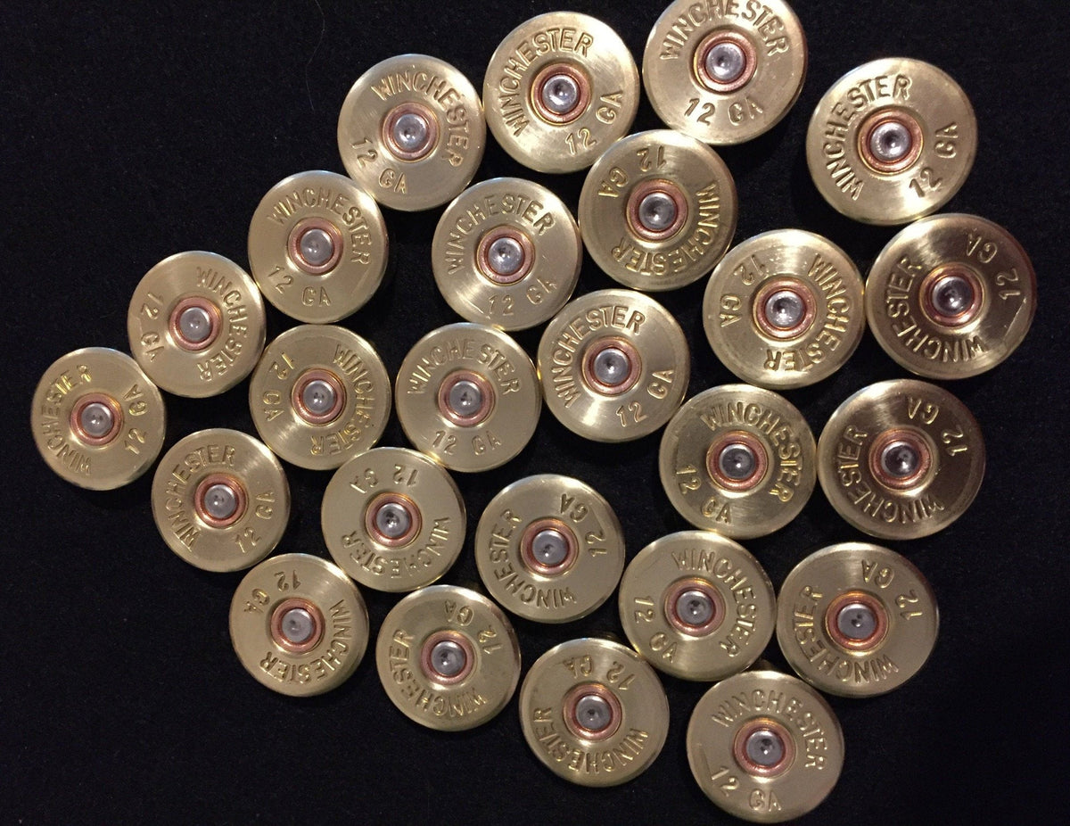 Many gold brass shell heads with "Winchester 12 GA" headstamps arranged on a black background