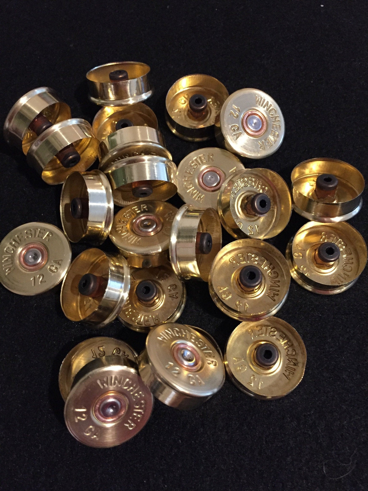 Gold brass shell heads with hollow primer pockets on a black background, some standing on edge