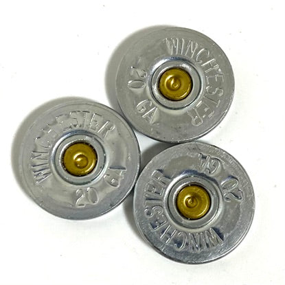 Three silver Winchester 20 gauge shotgun shell slices with brass primers arranged together