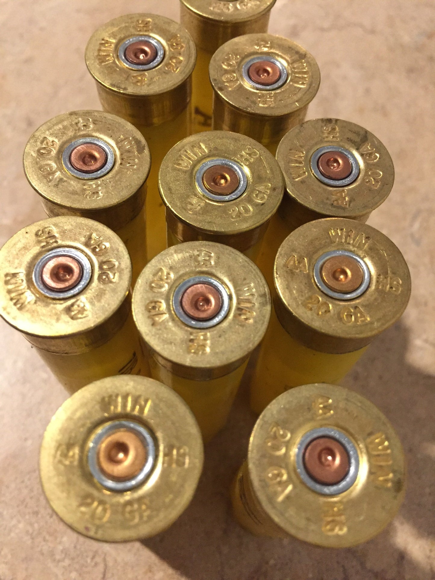 Overhead view of empty yellow Winchester 20-gauge cartridges, headstamps reading 'WIN 20 GA' clearly visible.