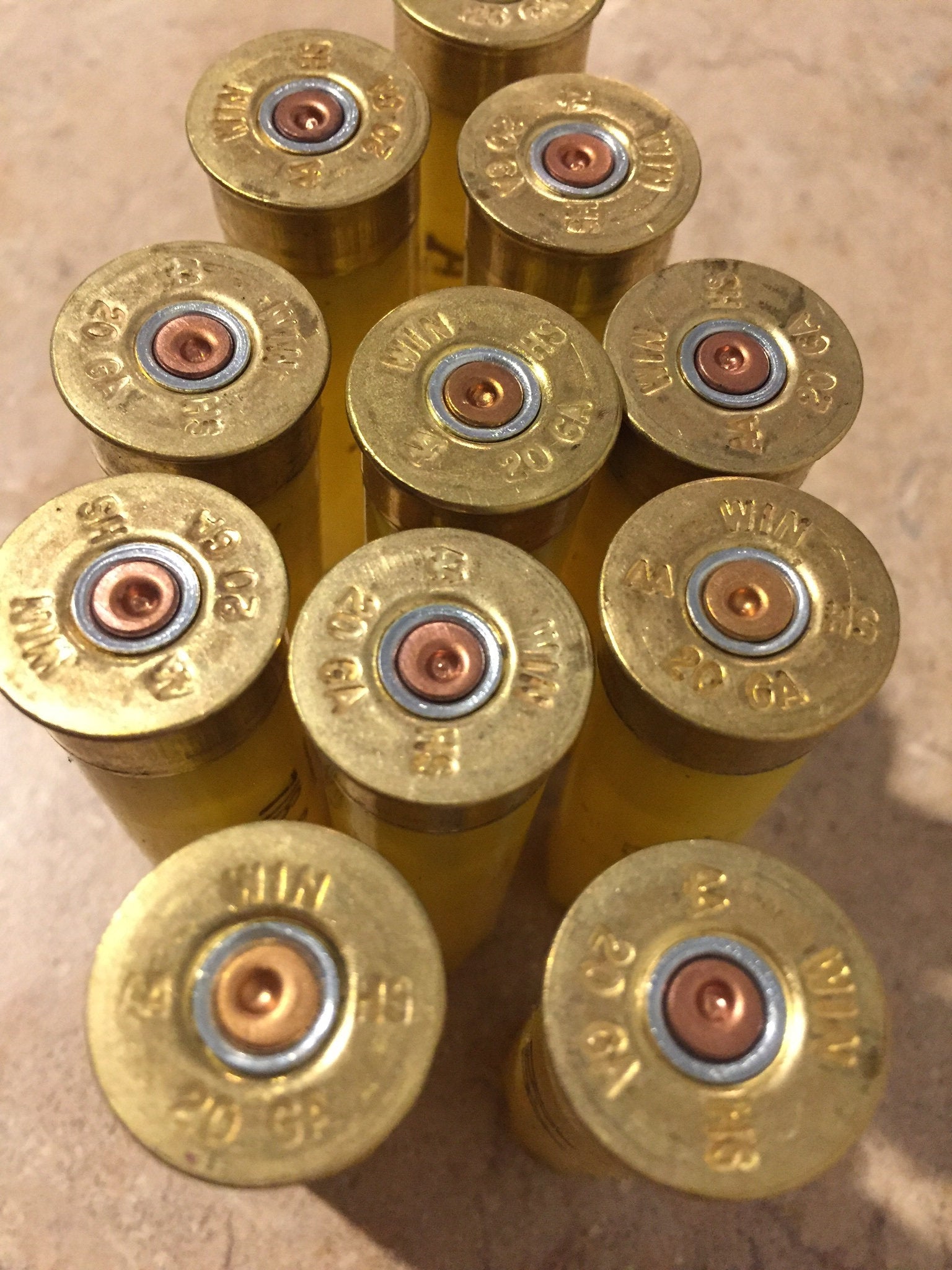 Overhead view of empty yellow Winchester 20-gauge cartridges, headstamps reading 'WIN 20 GA' clearly visible.