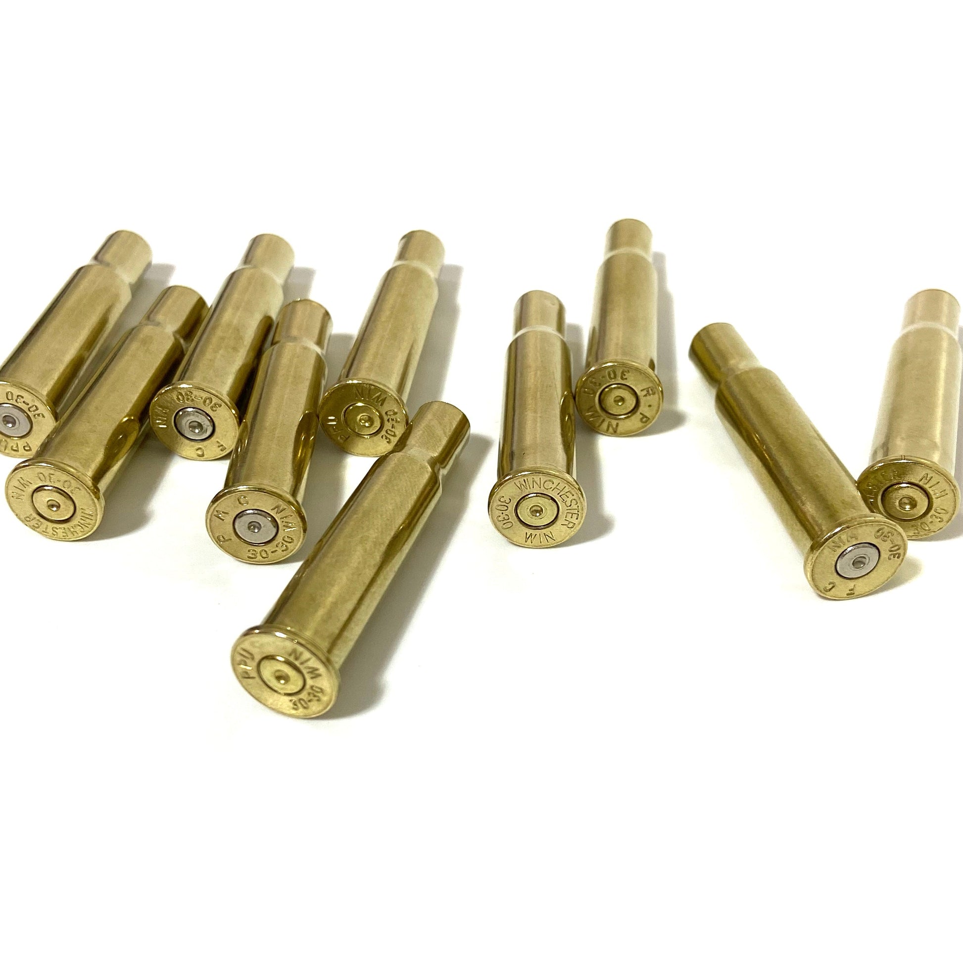 9 polished 30-30 Winchester brass casings, one standing to show headstamp, others lying flat, bright gold shine.
