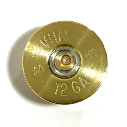 Closeup of a single gold Winchester AA 12 gauge shotgun shell headstamp, stamped ‘WIN AA HS 12 GA’