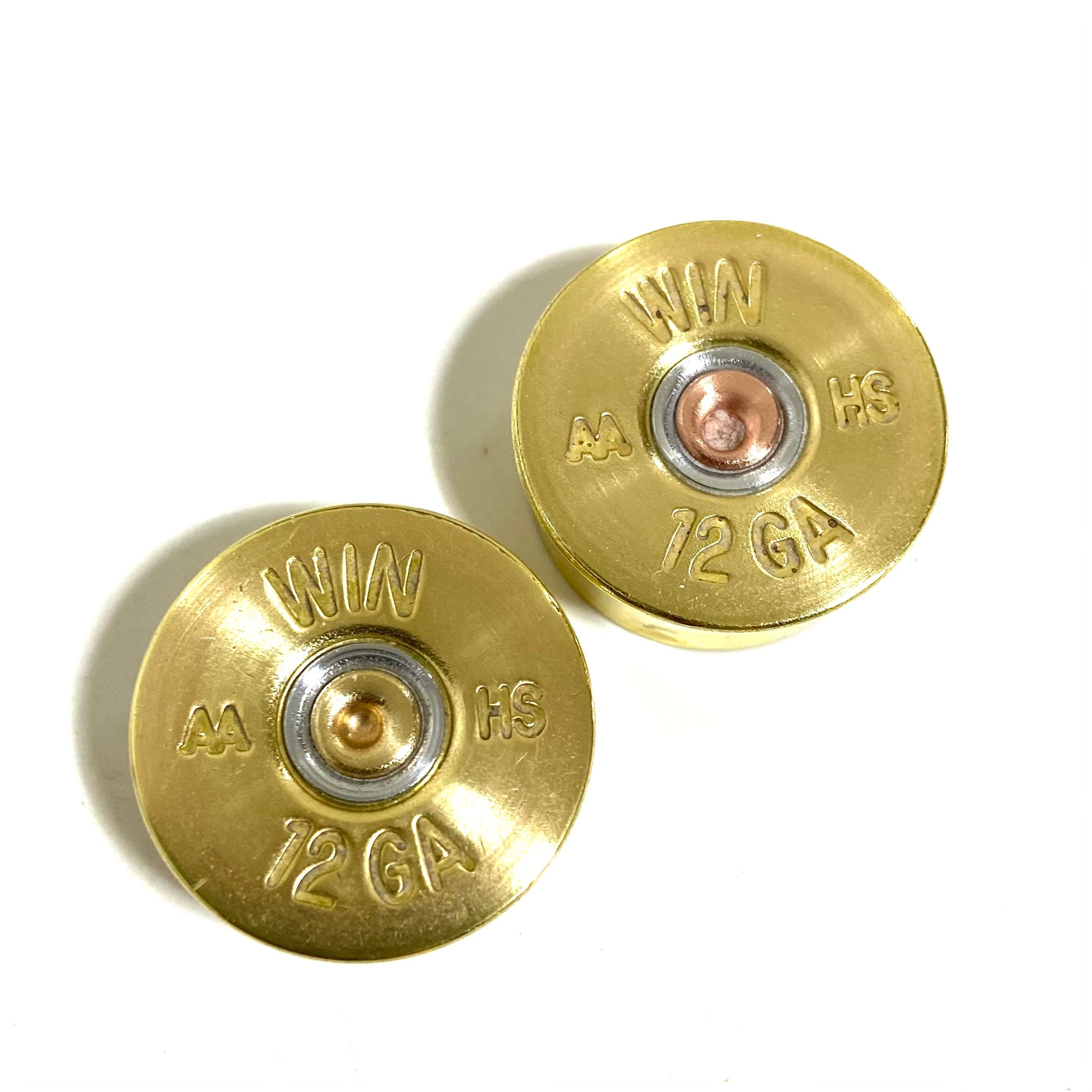 Two gold Winchester AA 12 gauge shotgun shell headstamps on a white background, showing ‘WIN AA HS 12 GA’ stampings