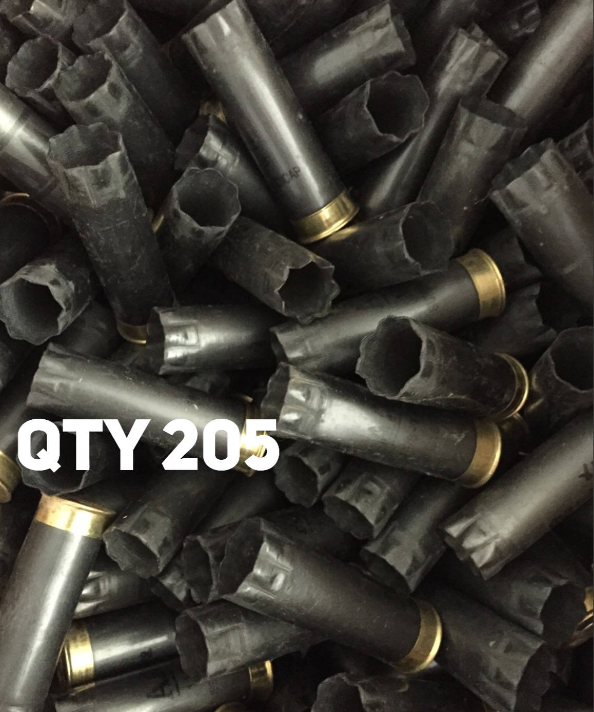Heap of spent gray Winchester AA 12 gauge shotgun shells with brass bases and bold white QTY 205 text overlay.