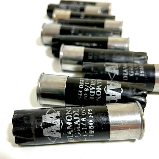 Row of empty black Winchester AA Diamond Grade hulls with silver high-brass bases on a white background.
