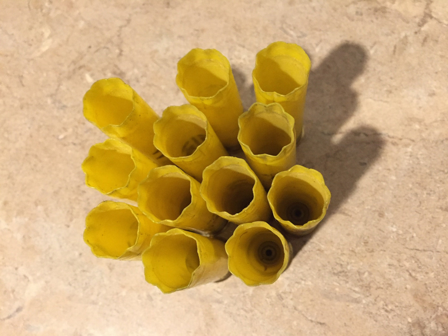 A cluster of used yellow hulls viewed from above, showing open star-crimped mouths and cast shadow.