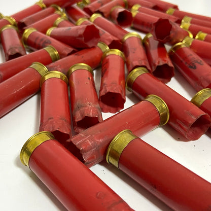 Close-up of Winchester red shotgun spent casings scattered at angles on a white surface with brass bases