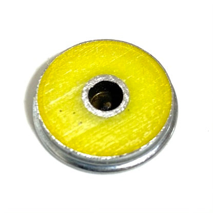 Backside of a shotgun shell slice showing yellow hull coating around a drilled brass center