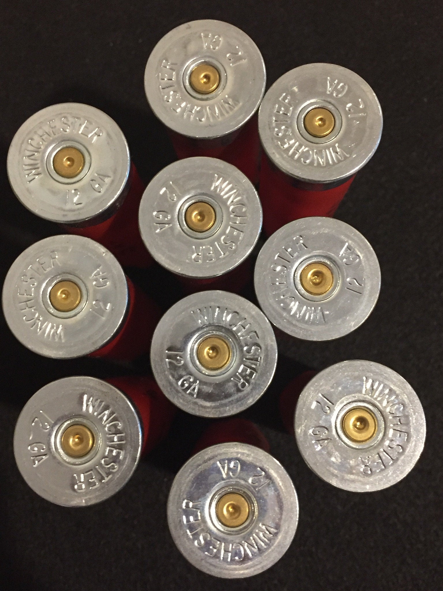 Nine red Winchester 12 gauge shotgun shells viewed from above showing silver headstamps