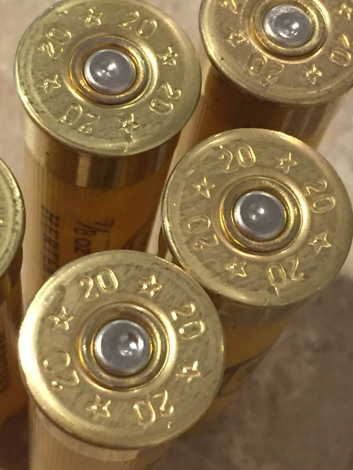 Two gold brass heads of yellow shotgun shells viewed close-up showing 20 gauge markings