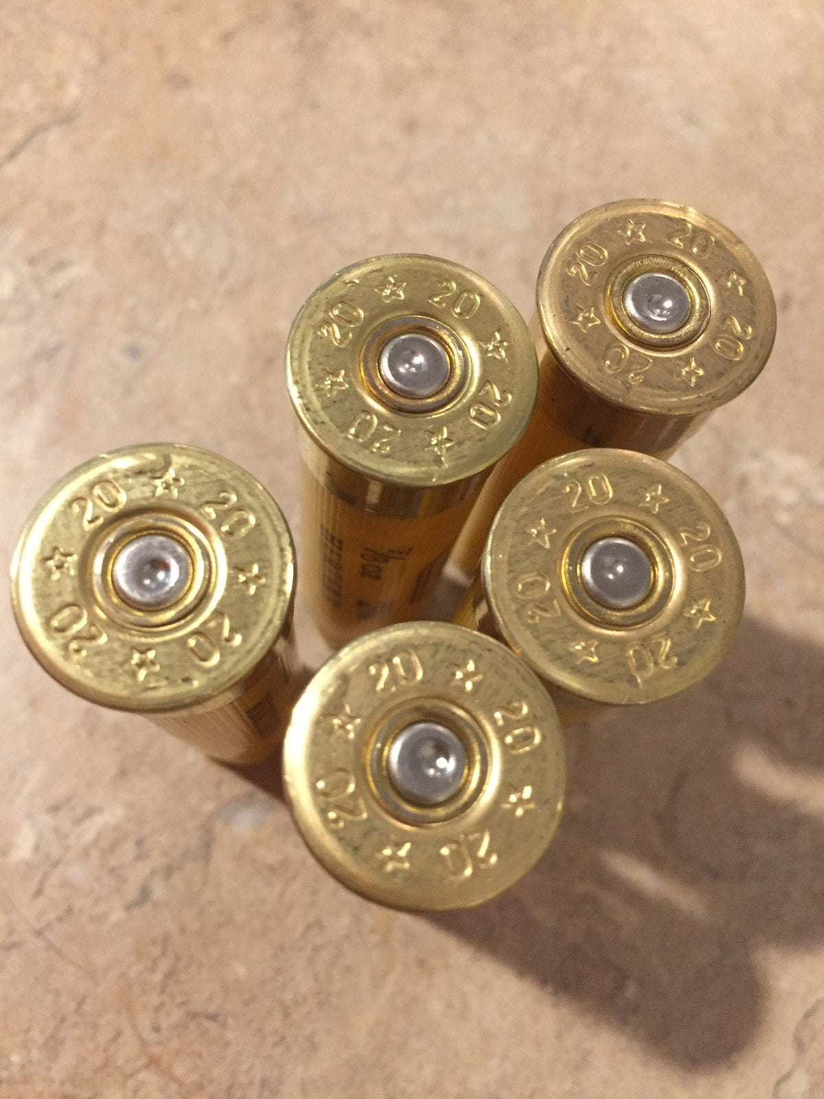 Close-up of 3 gold brass heads of yellow 20 gauge shotgun shells showing 20 gauge markings