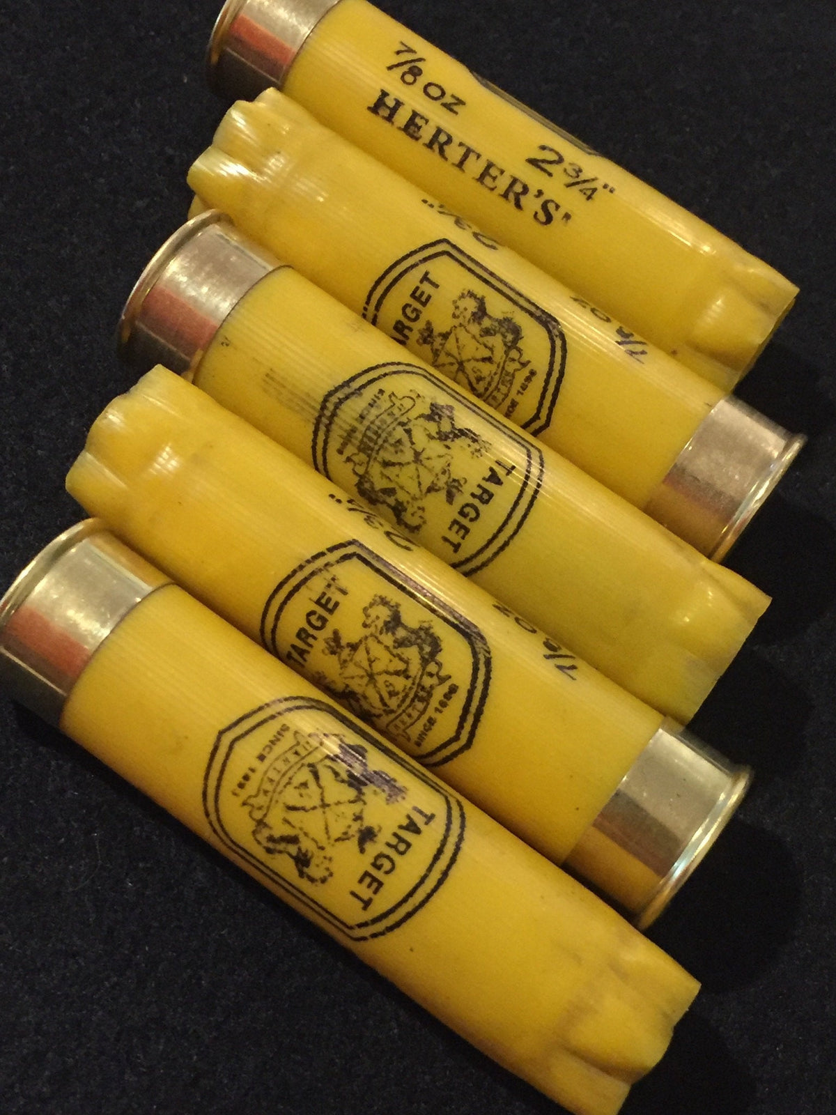 Yellow shotgun shell lying next to a wooden ruler showing its length